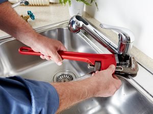 Expert Justcare technician repairing a kitchen faucet in Dubai.