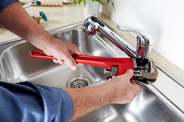 Expert Justcare technician repairing a kitchen faucet in Dubai.