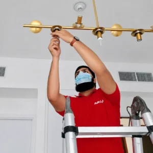 Light installation Dubai technician installing a modern chandelier ceiling light in a home
