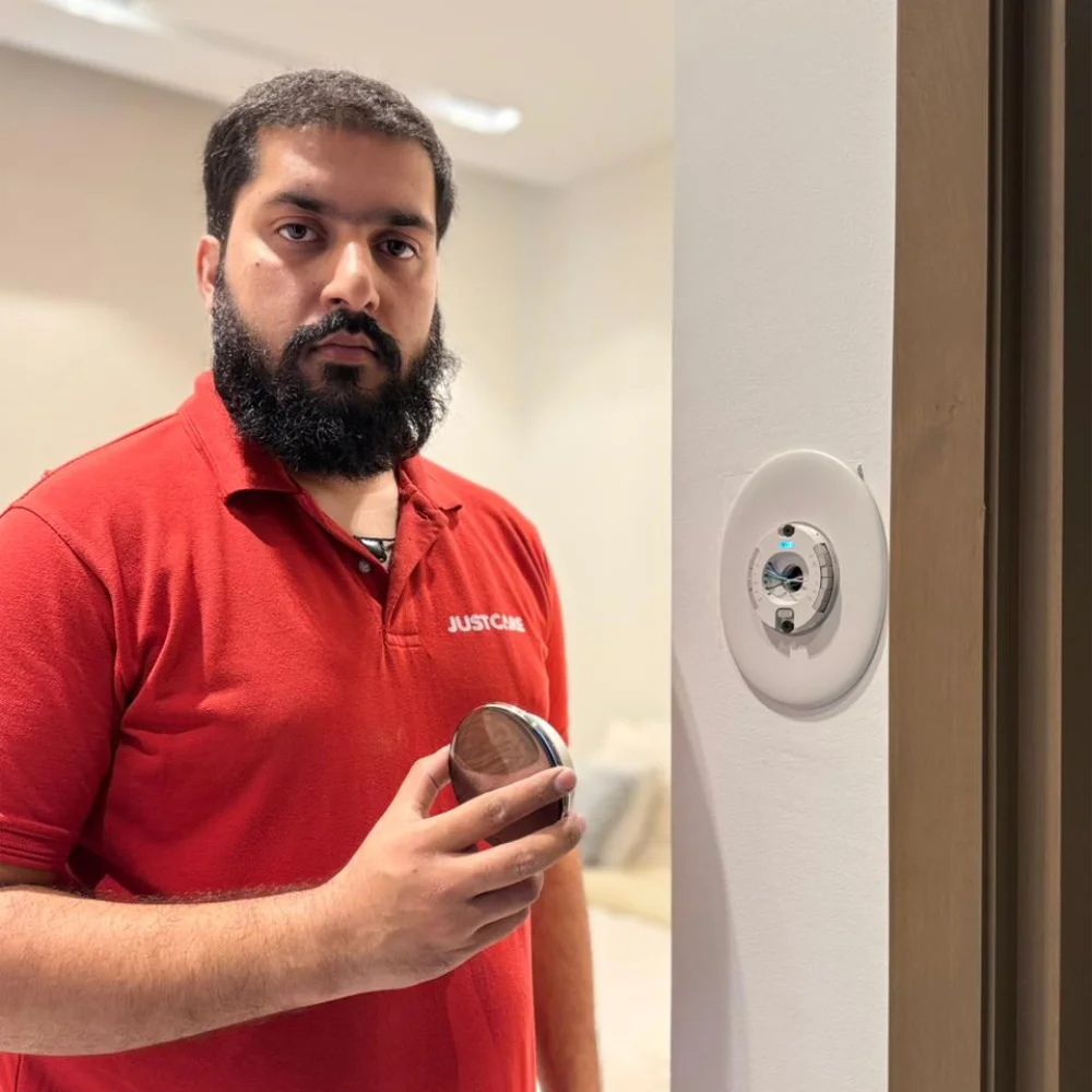 How to install a smart thermostat with a JustCare technician setting up a Nest thermostat on a wall in Dubai